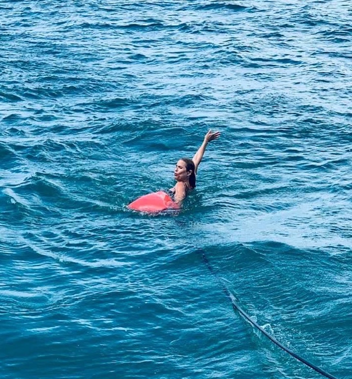 Denise floating by the sailboat in the water