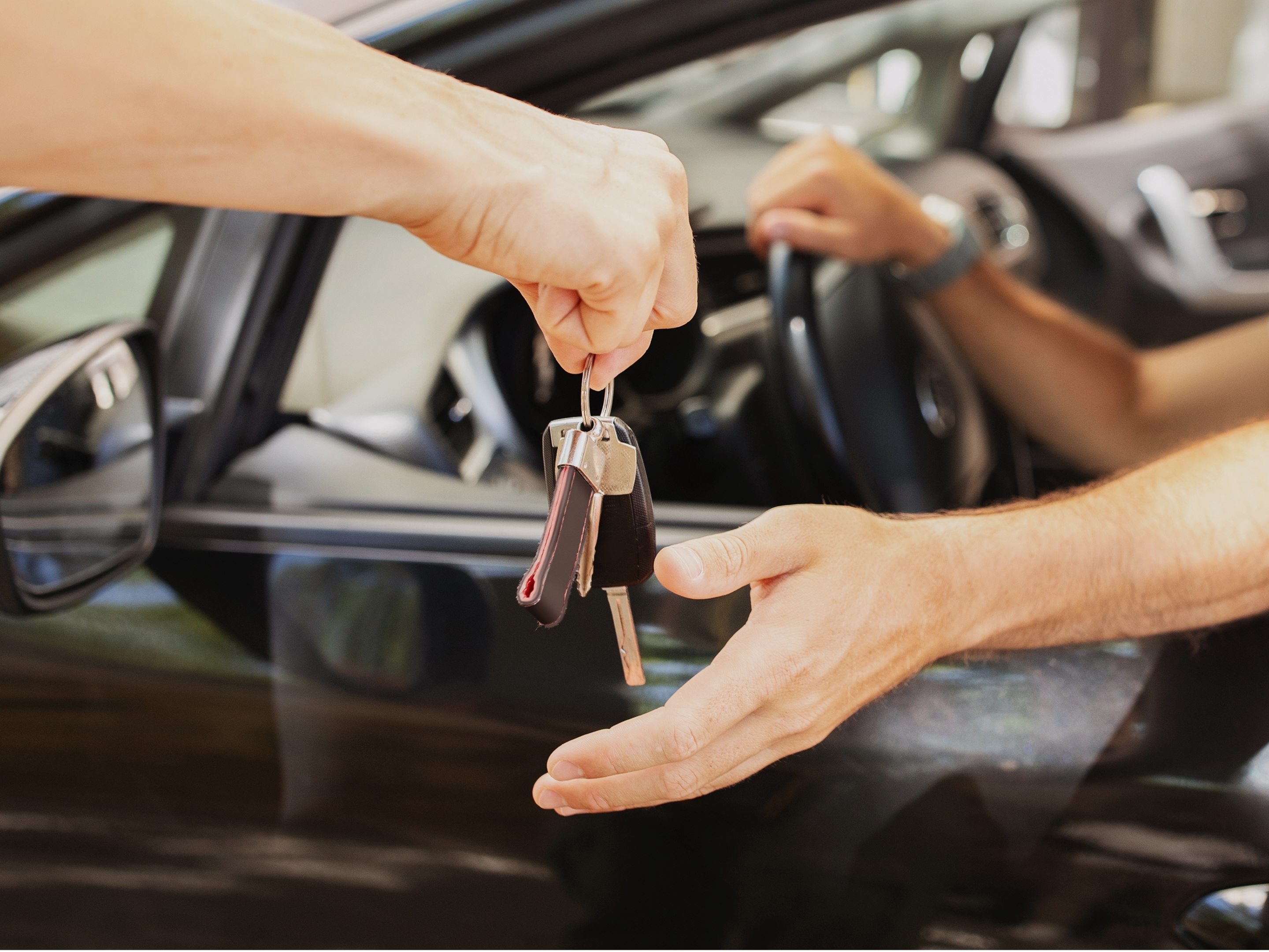 Hands exchanging car keys inside a vehicle, representing valet parking at Banneker in Washington, D.C. 