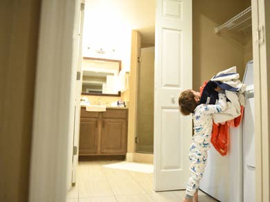 Kid trying to put laundry in a washing machine.