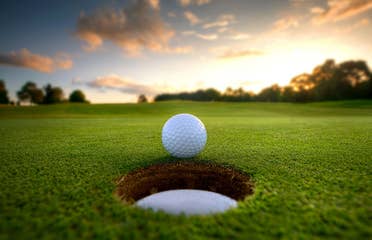 Golf ball close to hole on golf course.