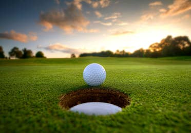 Golf ball close to hole on golf course.