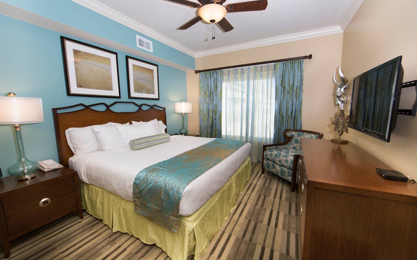 Master bedroom with large window, seating area, and flat screen TV in a Signature two-bedroom villa at Galveston Beach Resort