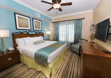 Master bedroom with large window, seating area, and flat screen TV in a Signature two-bedroom villa at Galveston Beach Resort