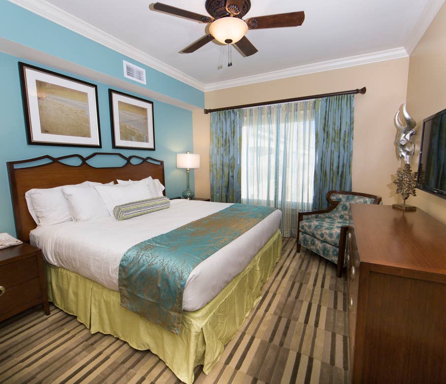 Master bedroom with large window, seating area, and flat screen TV in a Signature two-bedroom villa at Galveston Beach Resort