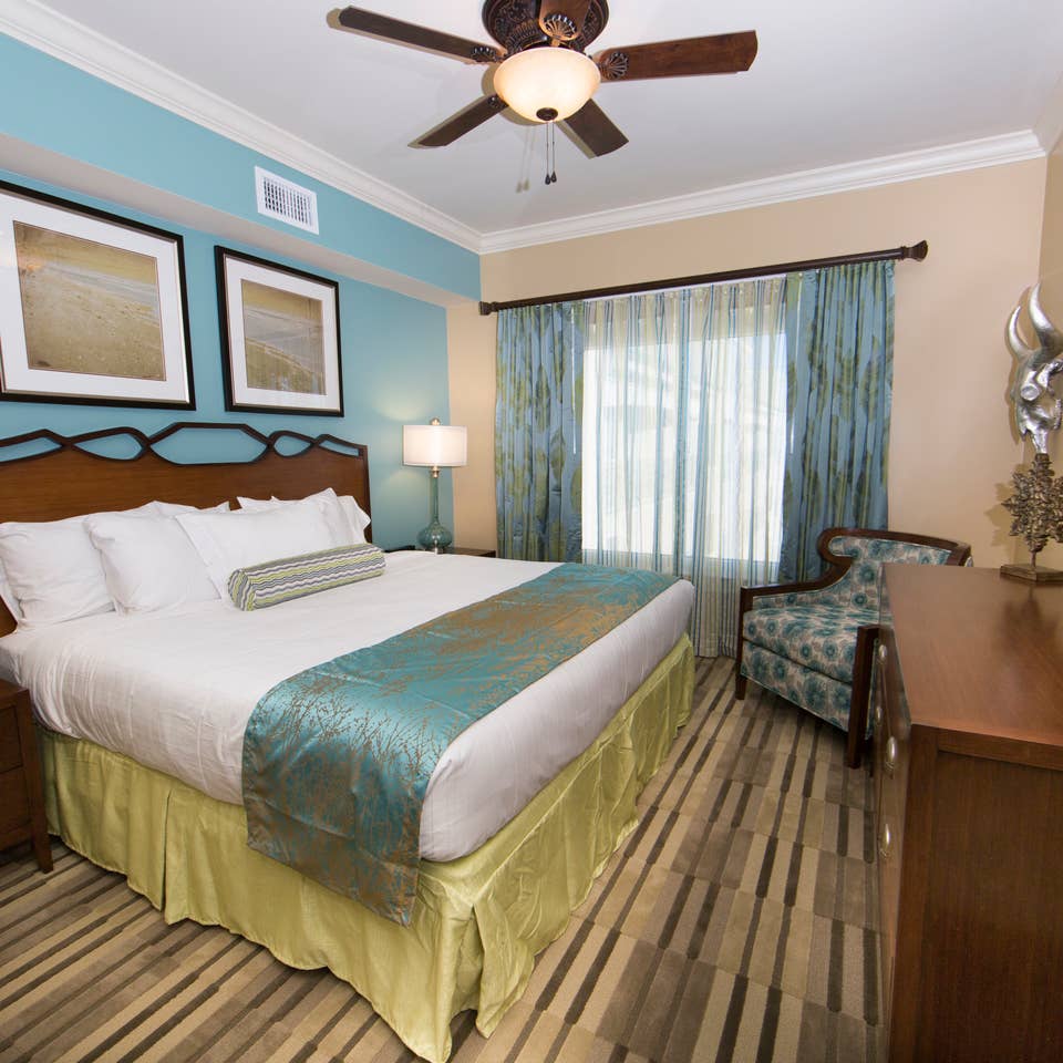 Master bedroom with large window, seating area, and flat screen TV in a Signature two-bedroom villa at Galveston Beach Resort