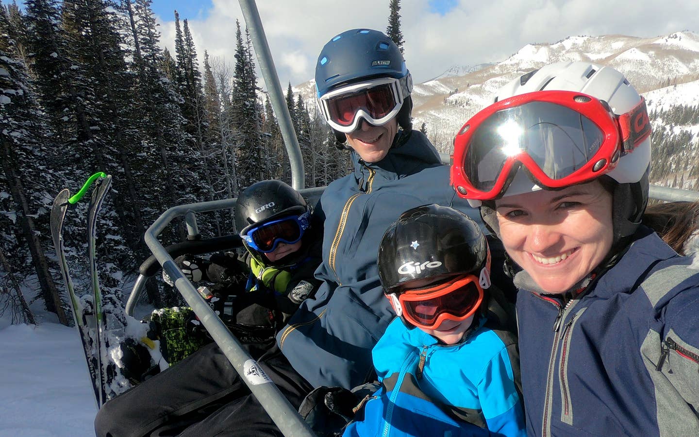 Author, Jessica Averett, and her family sit on the ski lift in winter apparel and ski gear.