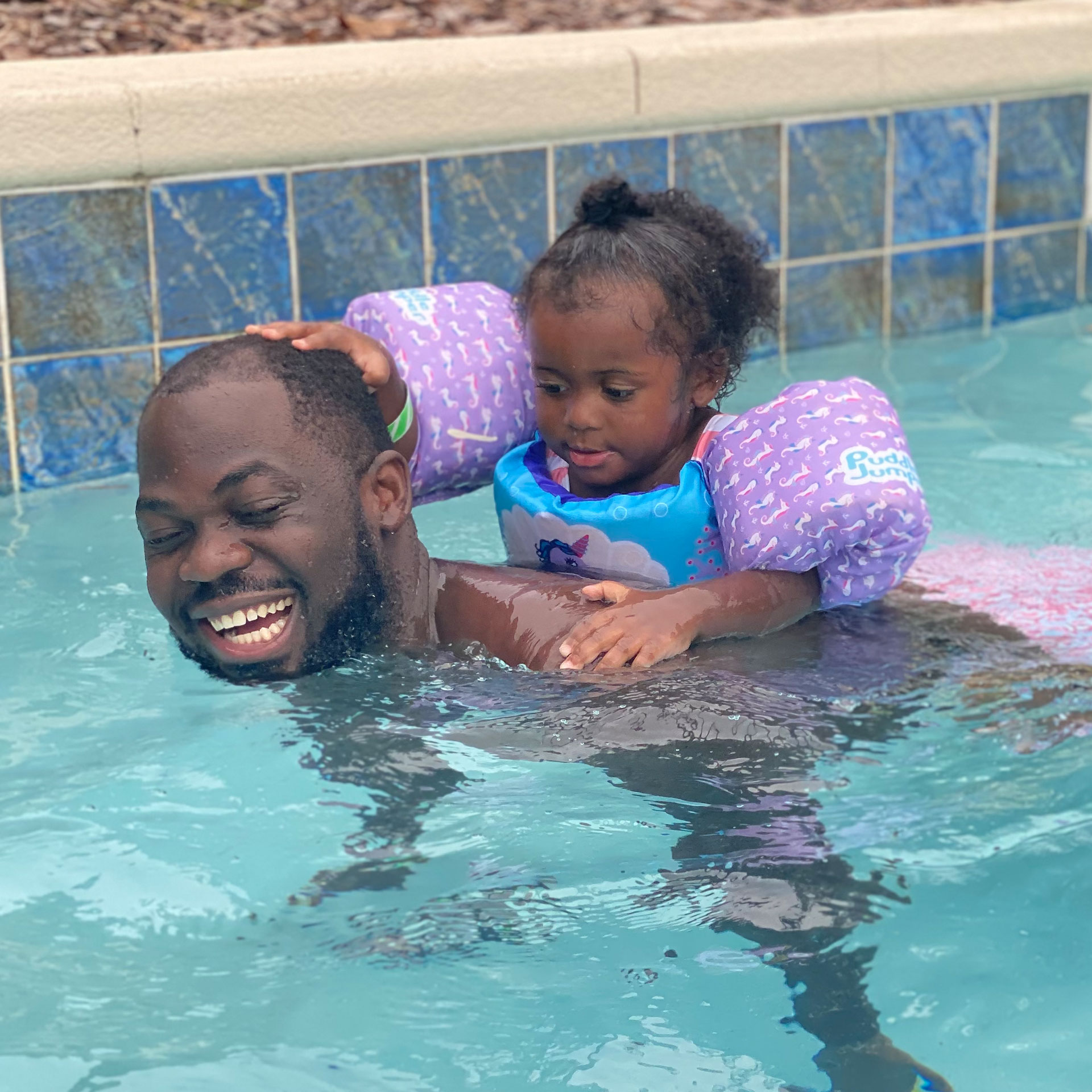 Author, Kimberly Gelin's husband (left), piggybacks his daughter, wearing her swimsuit and floaties in our lazy river at Orange Lake Resort in Florida.