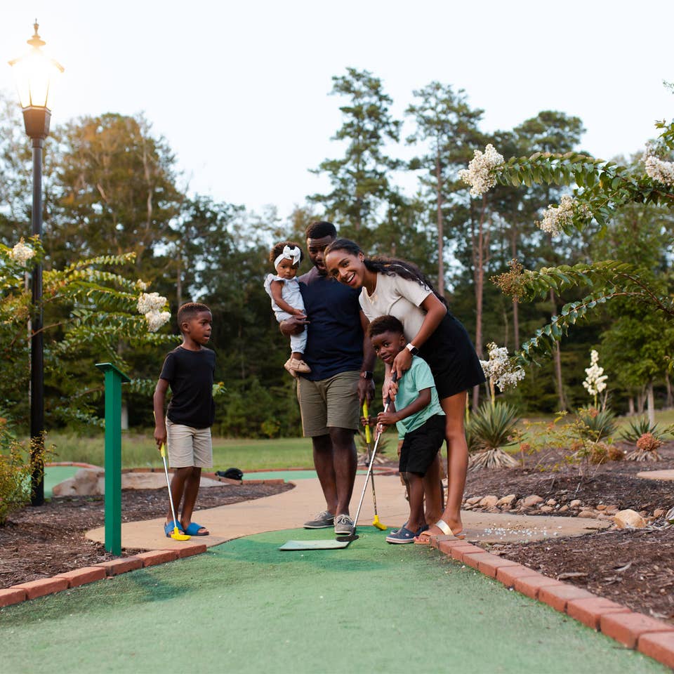 Family of five playing outdoor mini golf at Williamsburg Resort.