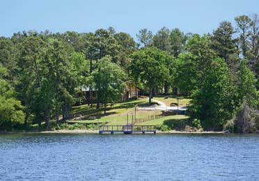 View of a cabin on the lake with a dock at the Lake O' the Wood Resort in Flint Texas.