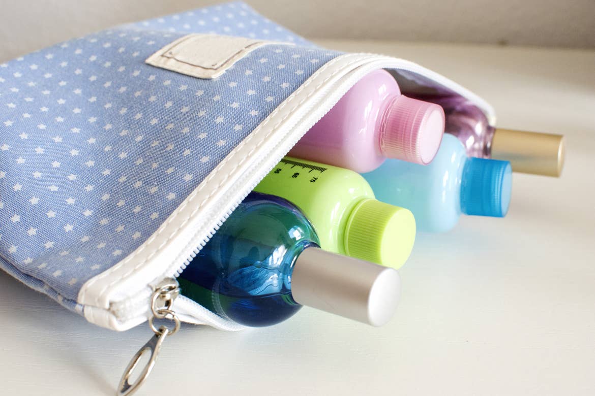 Blue travel toiletry bag with travel toiletries, small plastic bottles of hygiene products and perfume.
