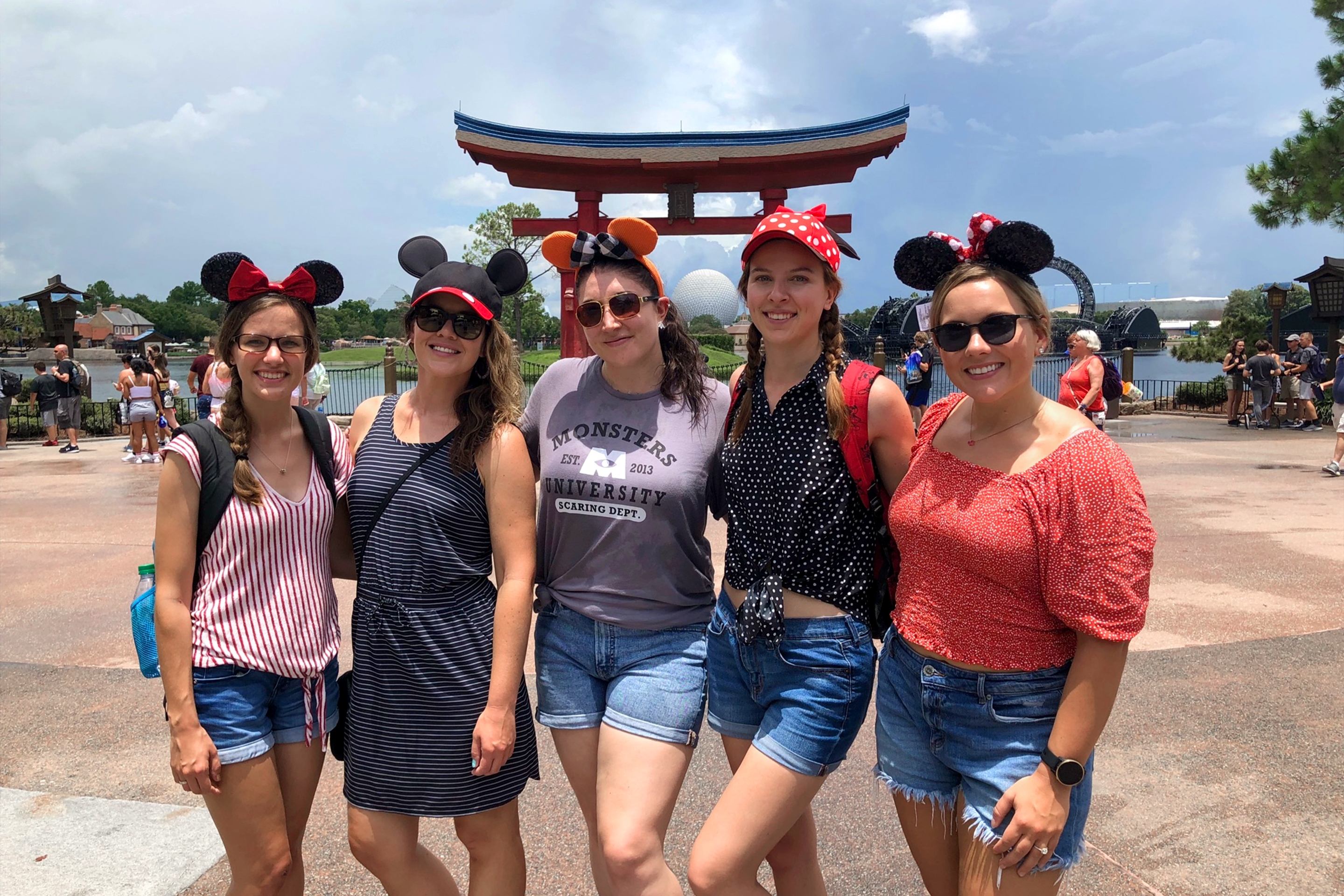 Five Caucasian women stand in a row wearing Mickey and Minnie ears near the Tori gat in the Japan pavilion at Epcot.