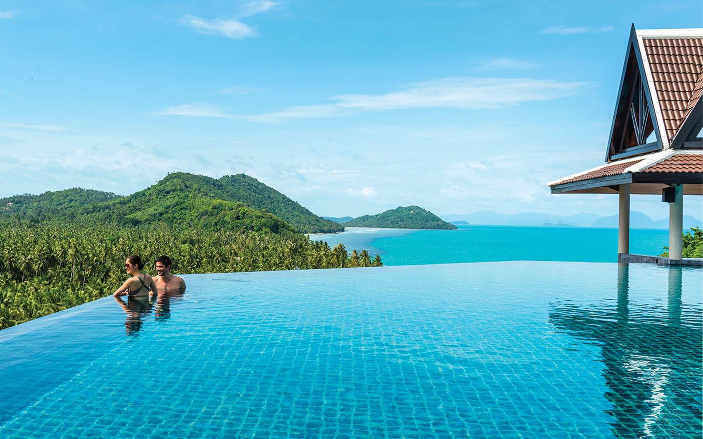 A couple looking over an infinity pool overlooking the ocean.