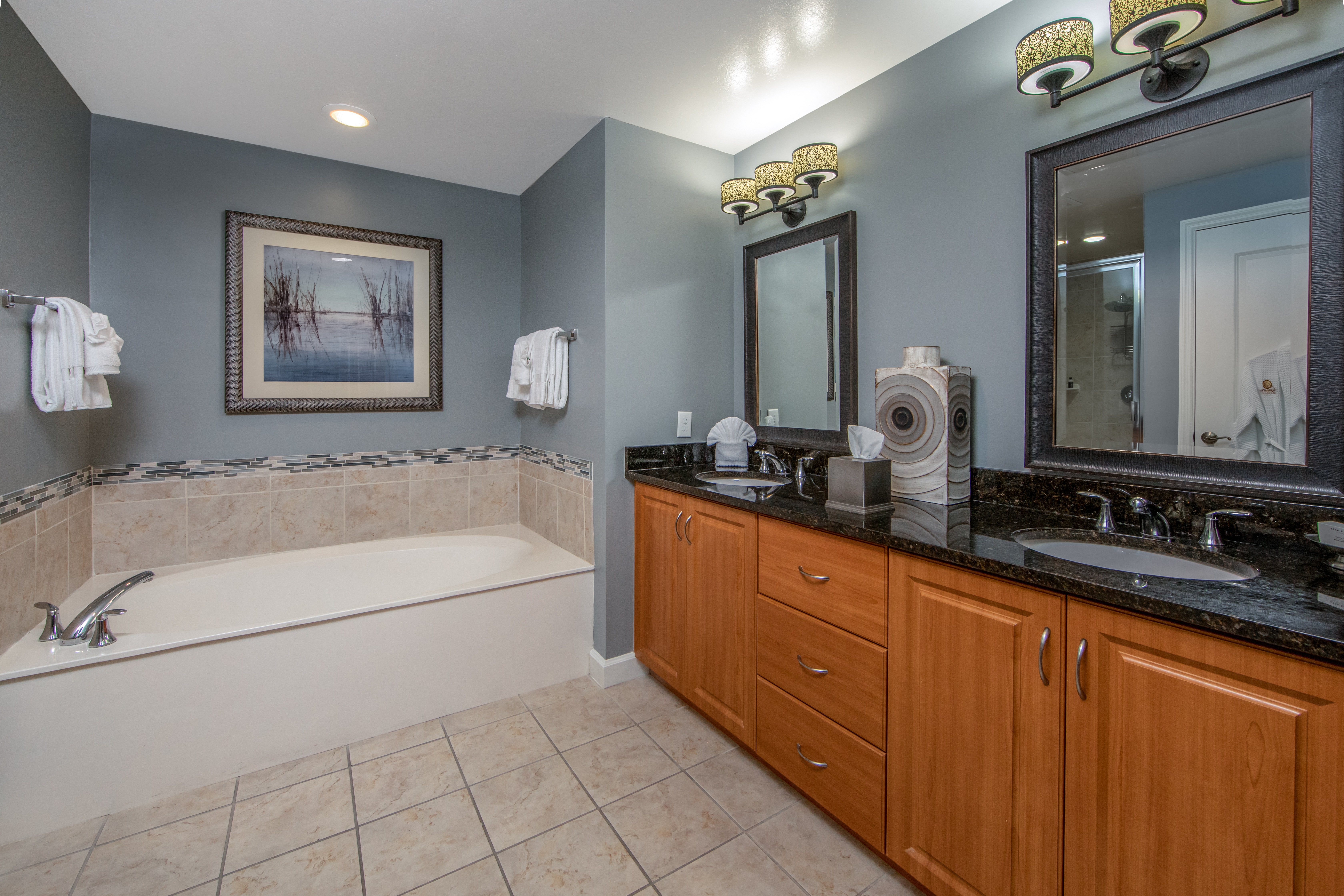 Bathroom with large bathtub and double sinks with two mirrors in a three-bedroom villa at Sunset Cove Resort in Marco Island, Florida