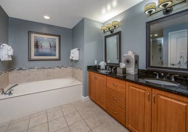 Bathroom with large bathtub and double sinks with two mirrors in a three-bedroom villa at Sunset Cove Resort in Marco Island, Florida