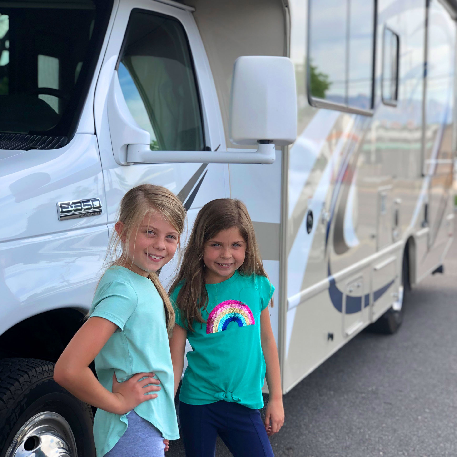 Author, Chris Johnstons' daughters, Kyndall (left), and Kyler (right) pose with in front of a white RV.