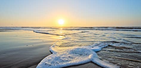 Wave crashing onto beach during sunset