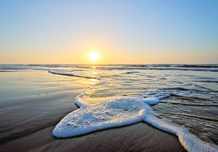 Wave crashing onto beach during sunset