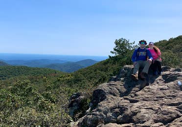 Featured Contributor, Ashley Fraboni (right) and Fiancé, Nicholas (left) sit atop a rock a Shenandoah National Park.