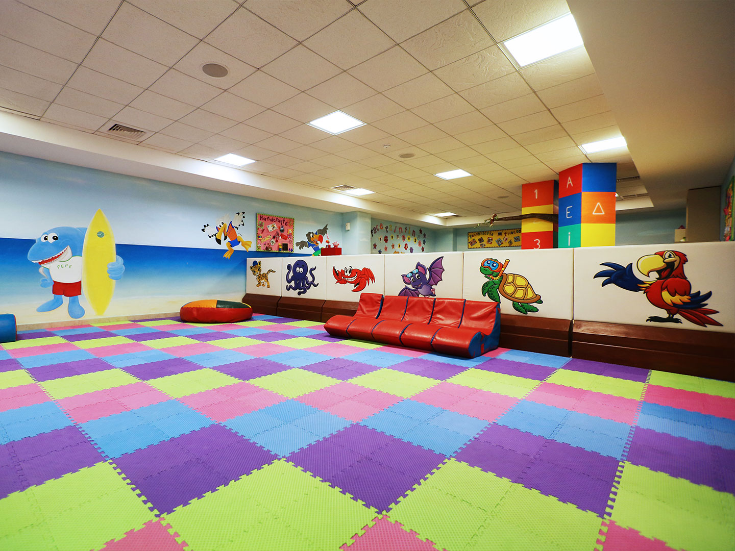 Game room with colorful foam flooring play area, red gaming chairs and a kid zone area at The Royal Haciendas in Playa del Carmen, Mexico