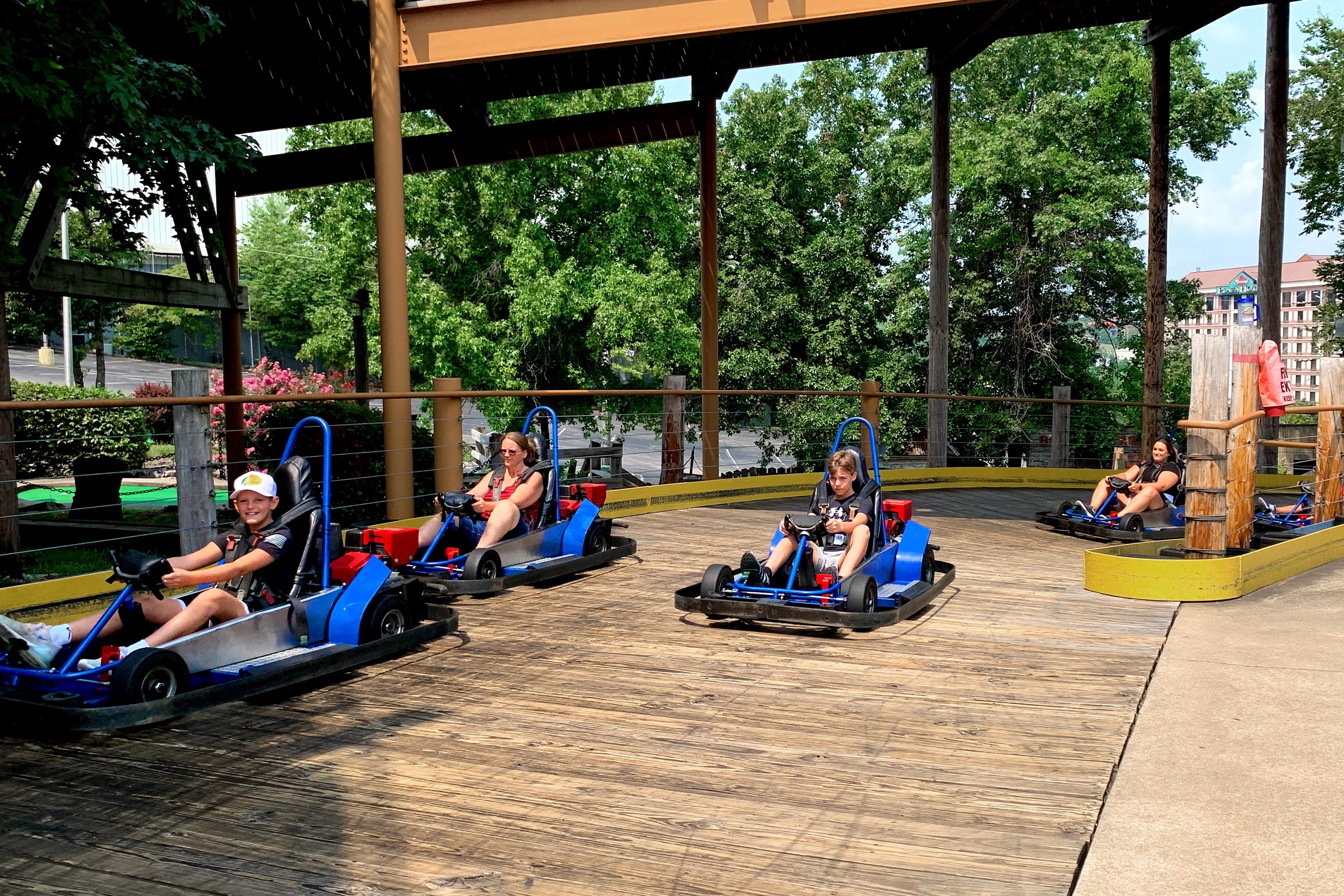Two boys and two women ride blue go karts on a track.