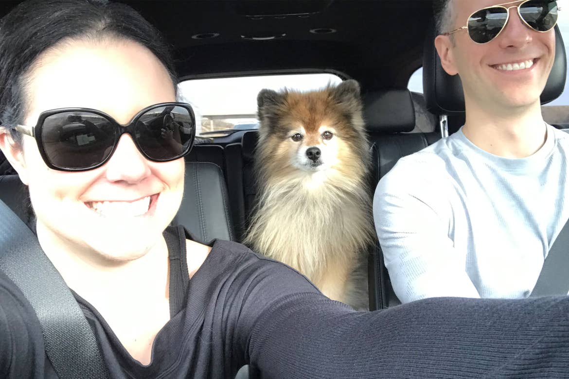 Authors, Lauren Layne and Anthony LeDonne, sit in their vehicle with Bailey the Pomeranian as they venture on their road trip.