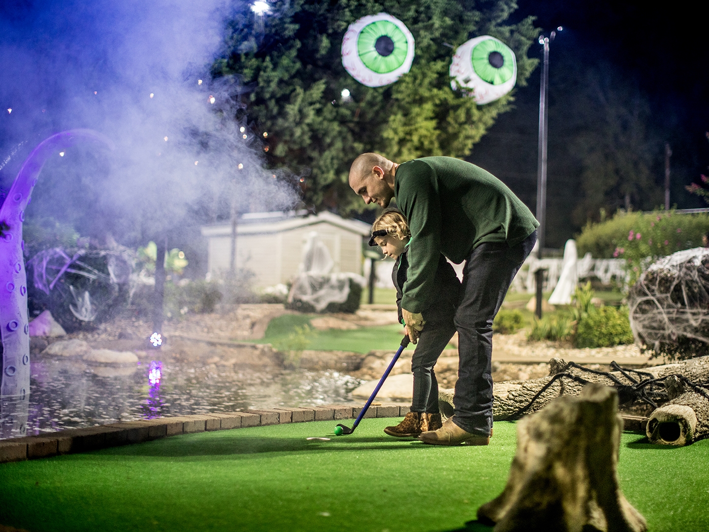 Father and child playing ghostly mini golf.