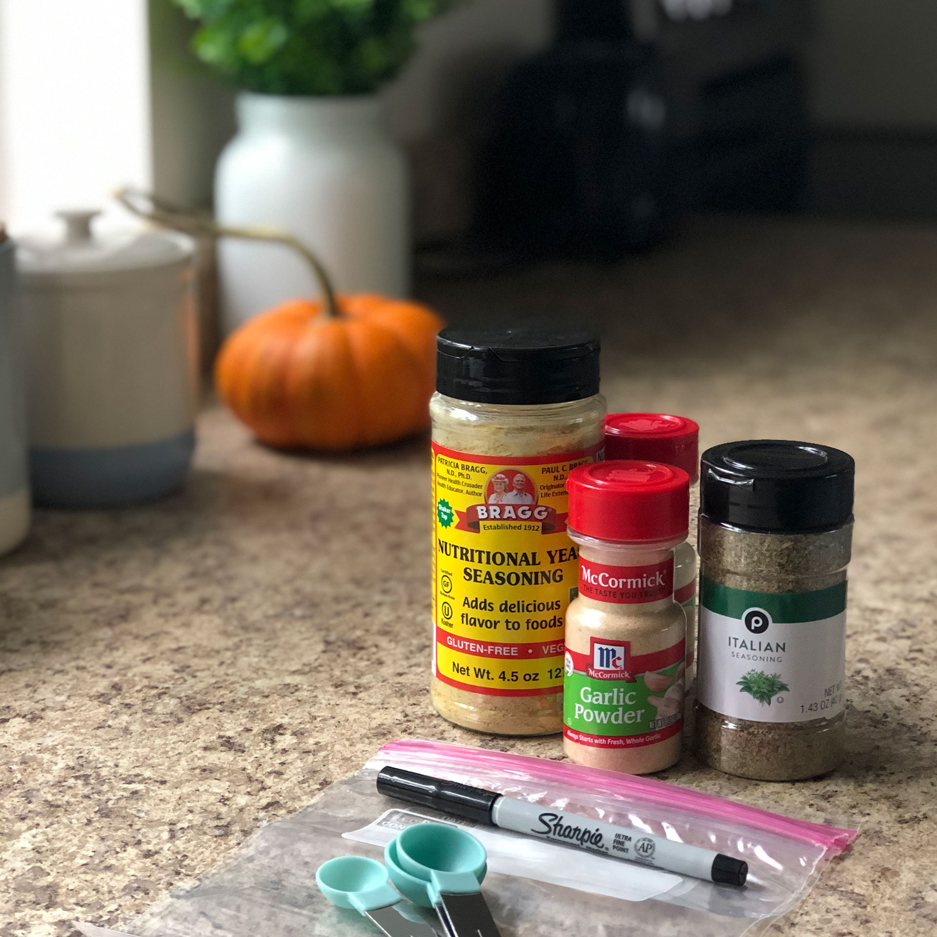 Spice containers sit on a countertop next to a Ziplock bag and Sharpie marker to be packed for the holiday vacation.