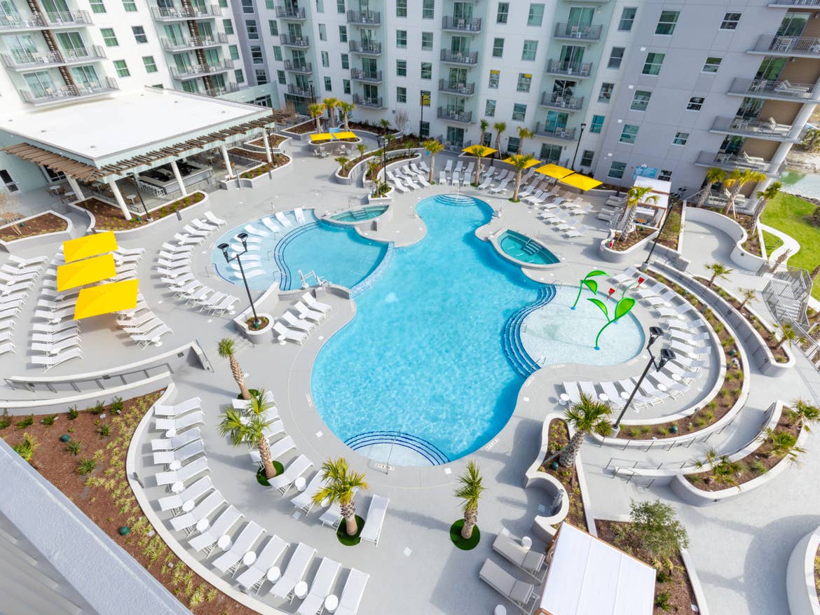 Aerial view of crisp white resort and bright blue pool in the middle.