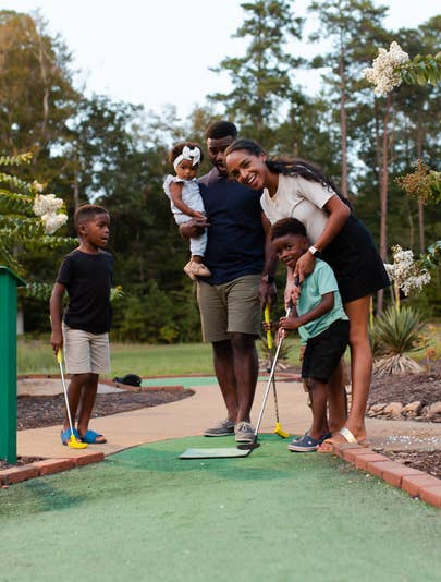 Mother teaching son how to putt at a miniature golf course at Holiday Inn Club Vacations Williamsburg Resort