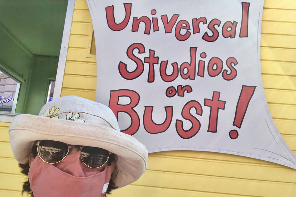 Author, Rona, stands in front of a yellow building with the sign, 'Universal Studios or Bust!'