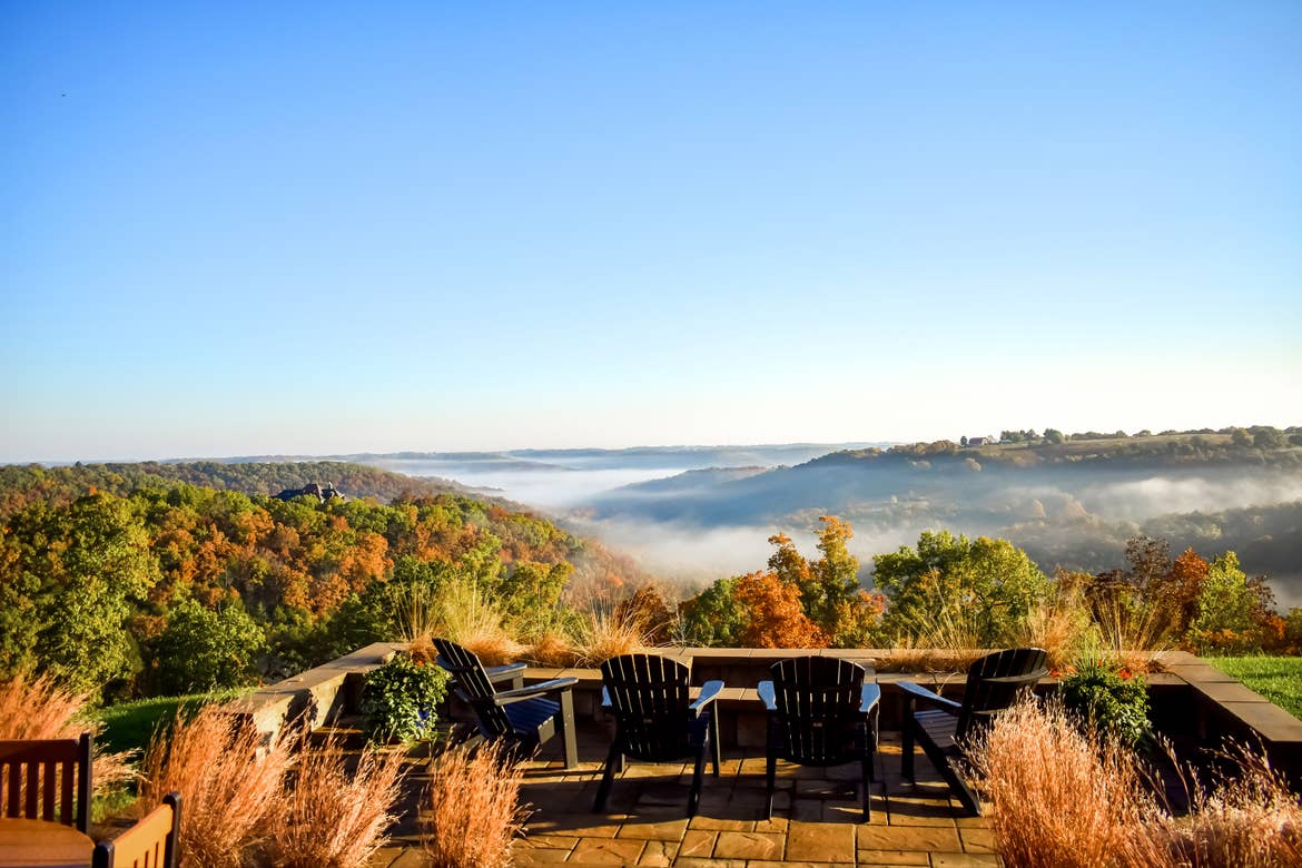 Several Adirondack chairs overlook fall foliage in Branson, MO.