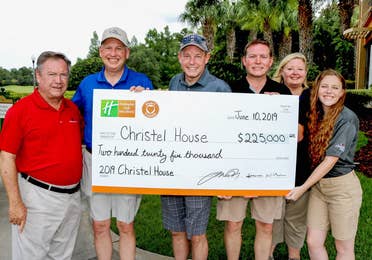 Group of people holding a large presentation check for $225,000 made payable to Christel House
