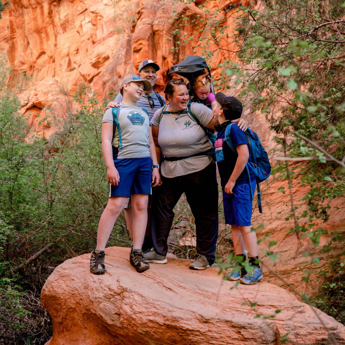 Featured Contributor, Melody Forsyth (middle), backpacks with her family on an orange rock formation.