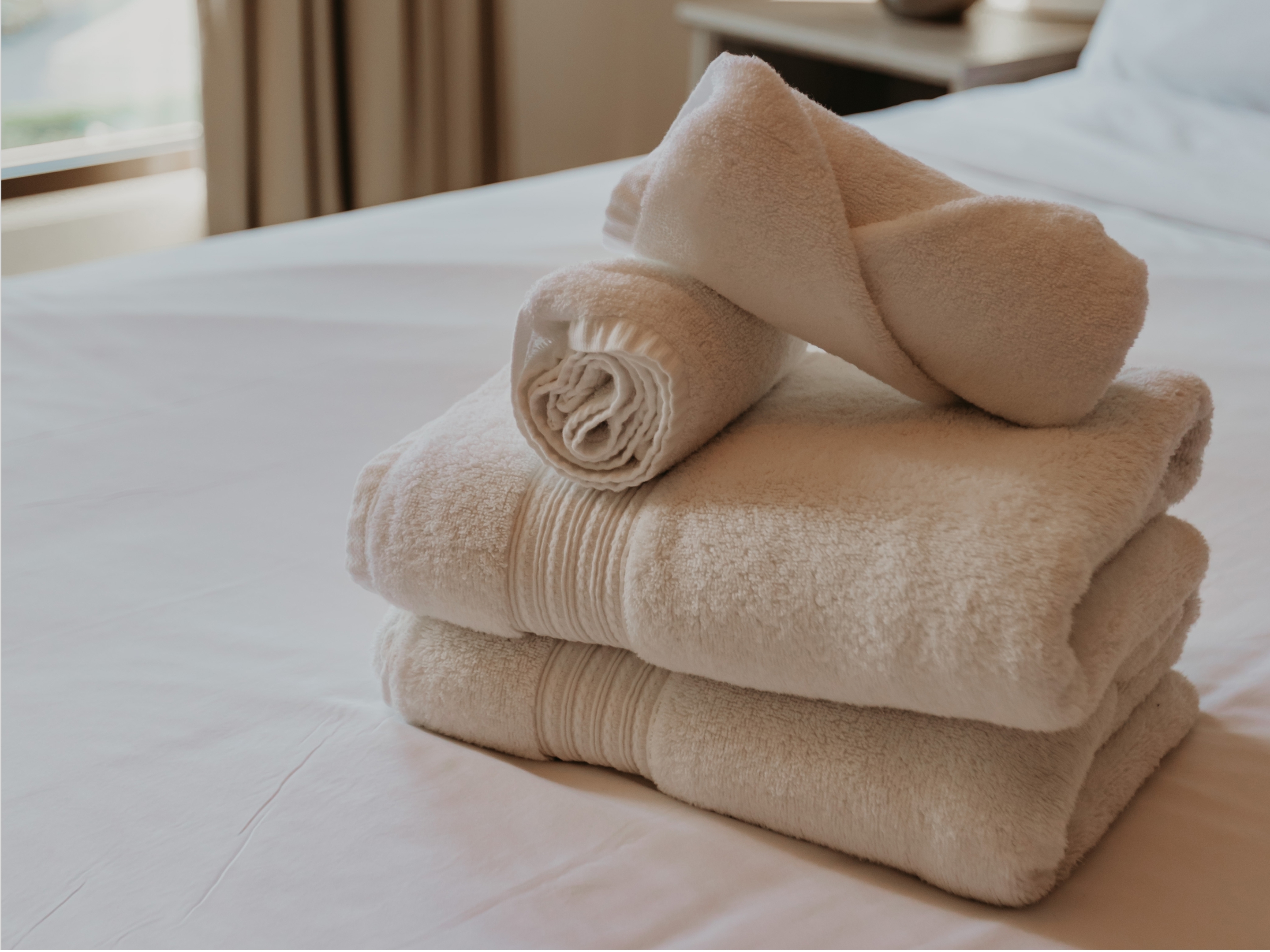 Folded white towels arranged on a neatly made guest room bed at Banneker. 