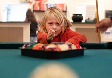 A young child at a pool table