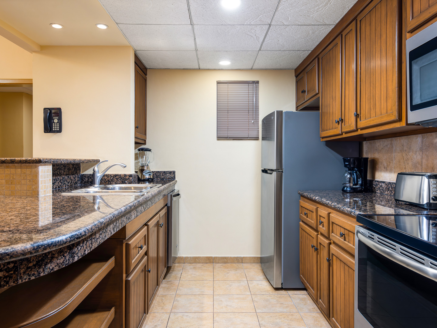 Full kitchen with granite counters, wood cabinets, and appliances.