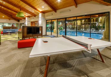 Table tennis and television in a game room with doors looking out to a pool.