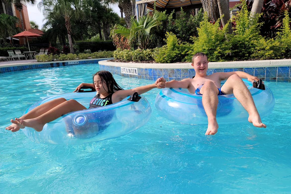 A young boy (right) and a young girl (left) sit in inner tubes while floating down a lazy river.