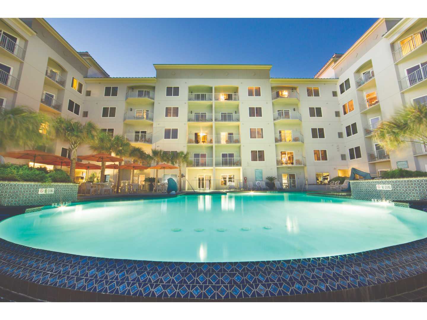 Evening view of a hotel courtyard with illuminated swimming pool.