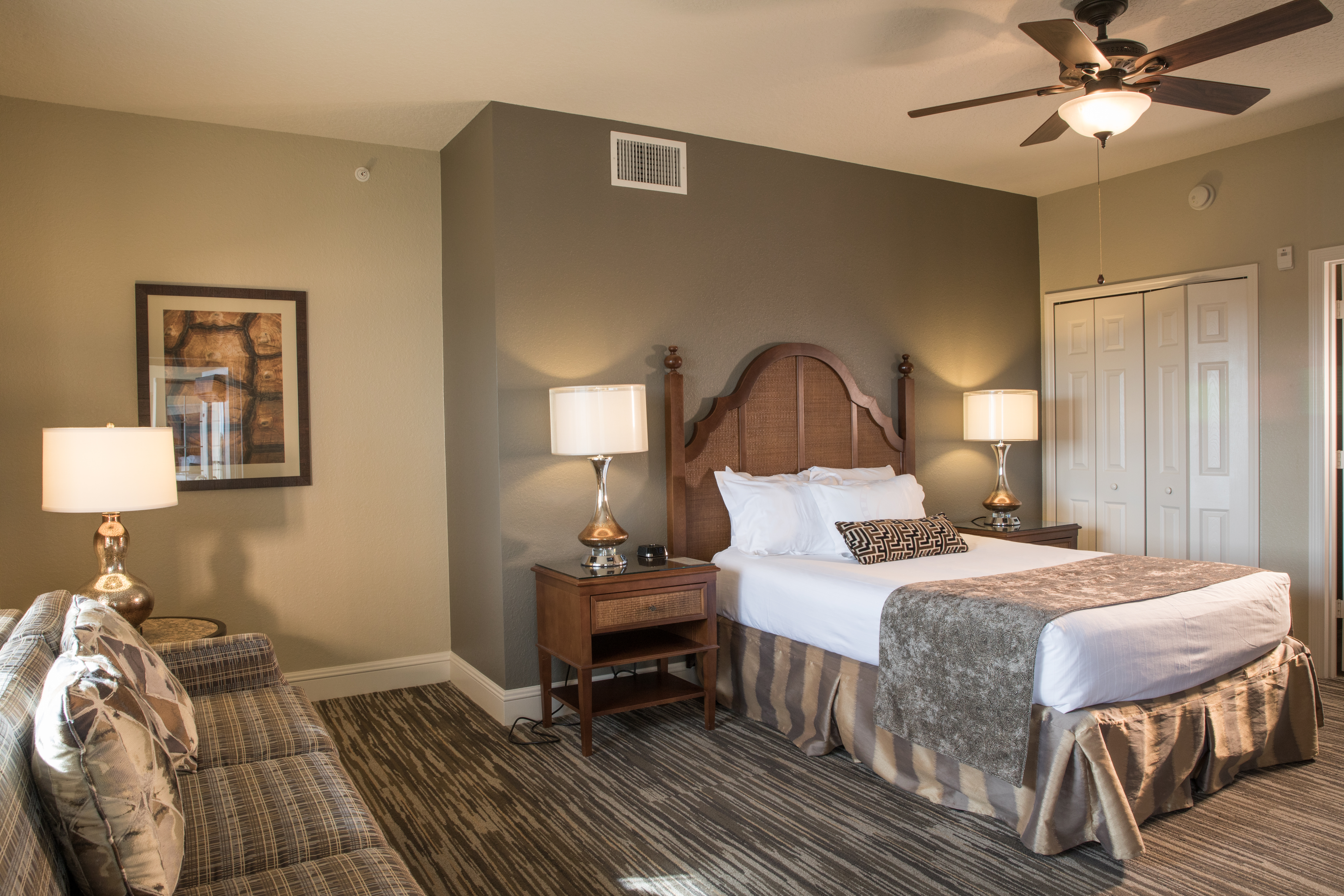 Bedroom with ceiling fan and seating area in a four bedroom Signature villa in River Island at Orange Lake Resort near Orlando, Florida