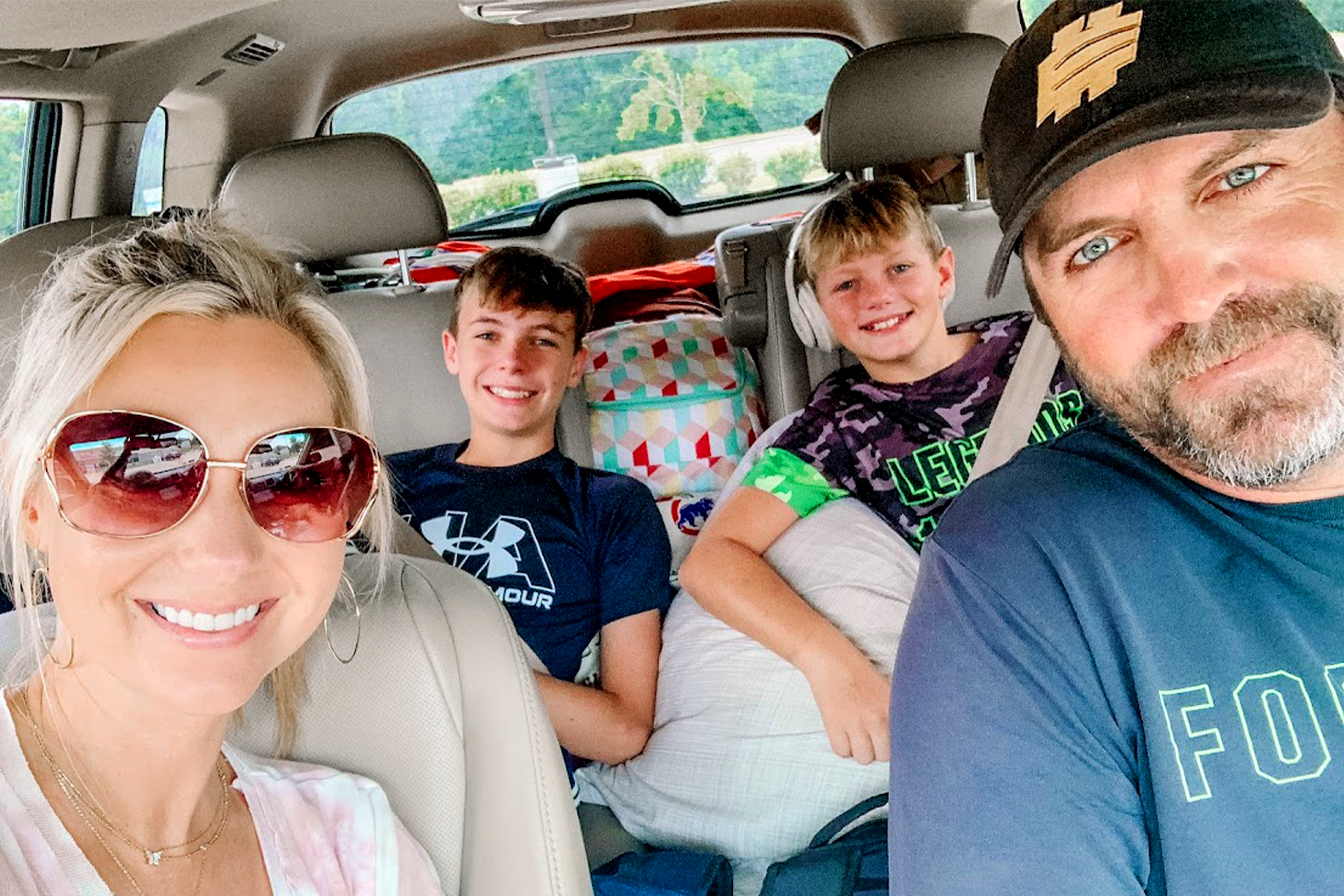 A woman, two boys, and a man sit inside a car.