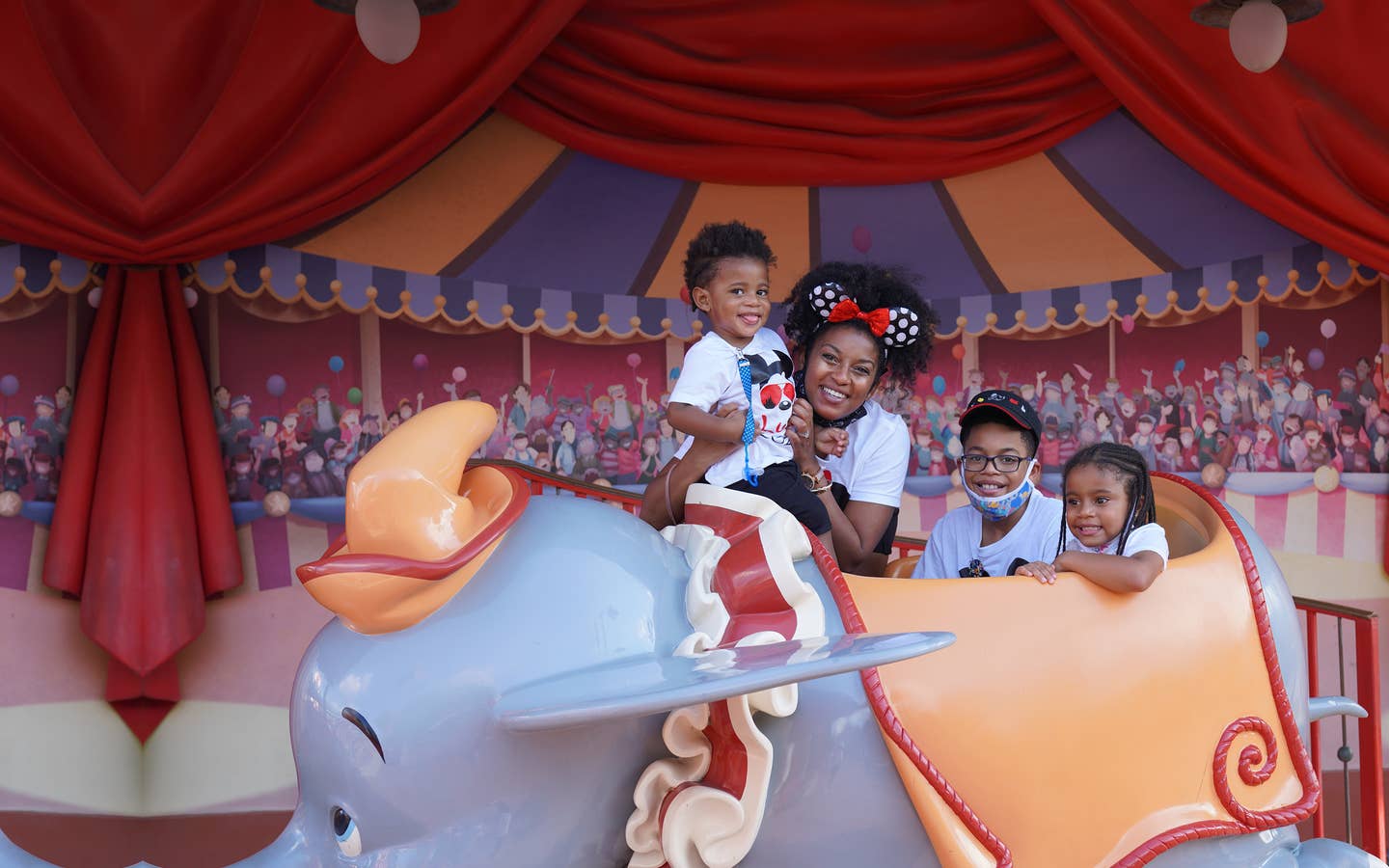 Featured Contributor, Tina Meeks, poses with her daughter and sons on a Dumbo ride vehicle located in Magic Kingdom at Walt Disney World resort.