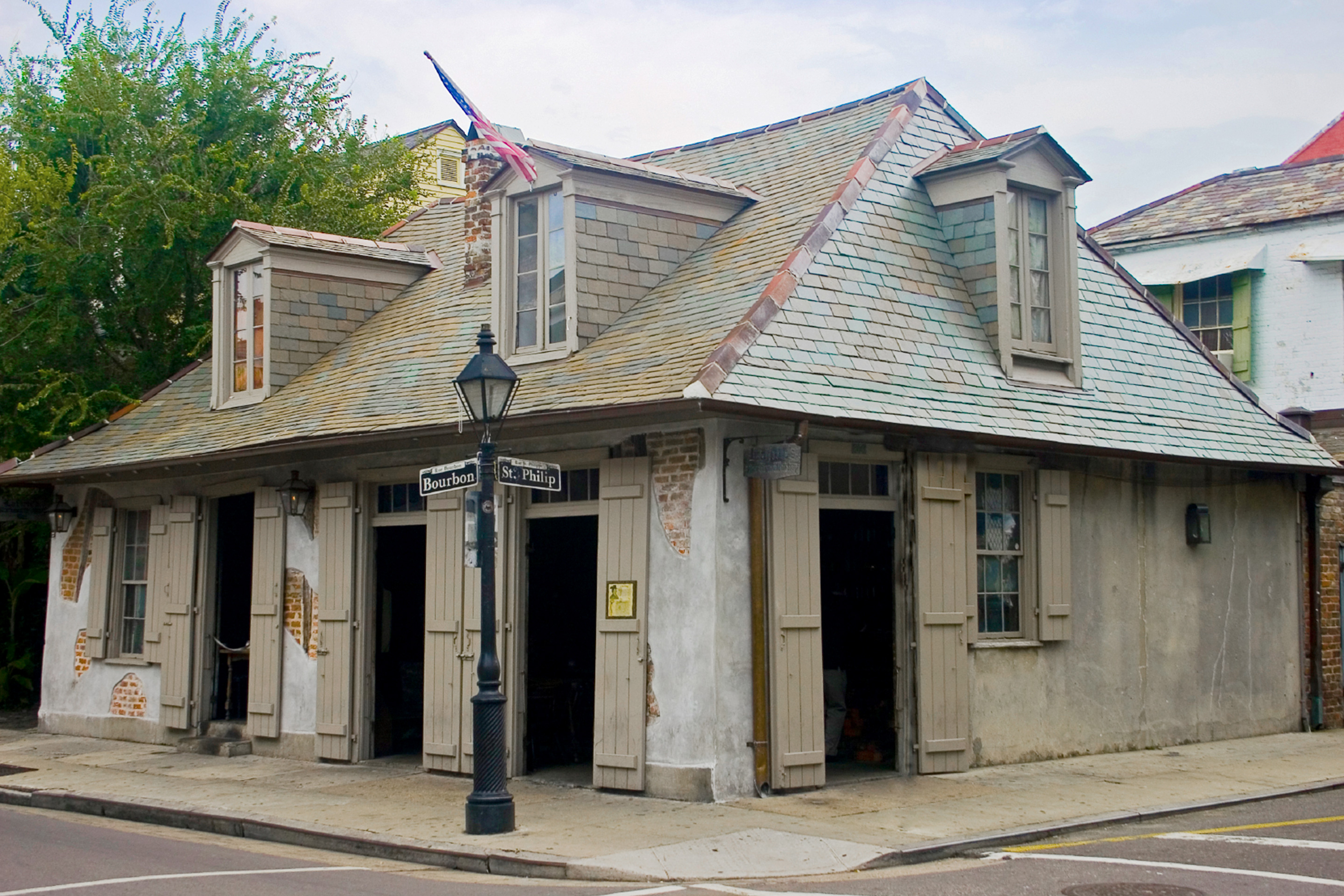 The exterior of LaFitte's Blacksmith Shop Bar is constructed of various brick and mortar with doorways that open like wooden shutters.
