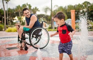 Author, Danny Pitaluga (left), and son, Joey (right), wear their swimsuits near a fountain park area at our Orange Lake Resort located in Orlando, Florida.