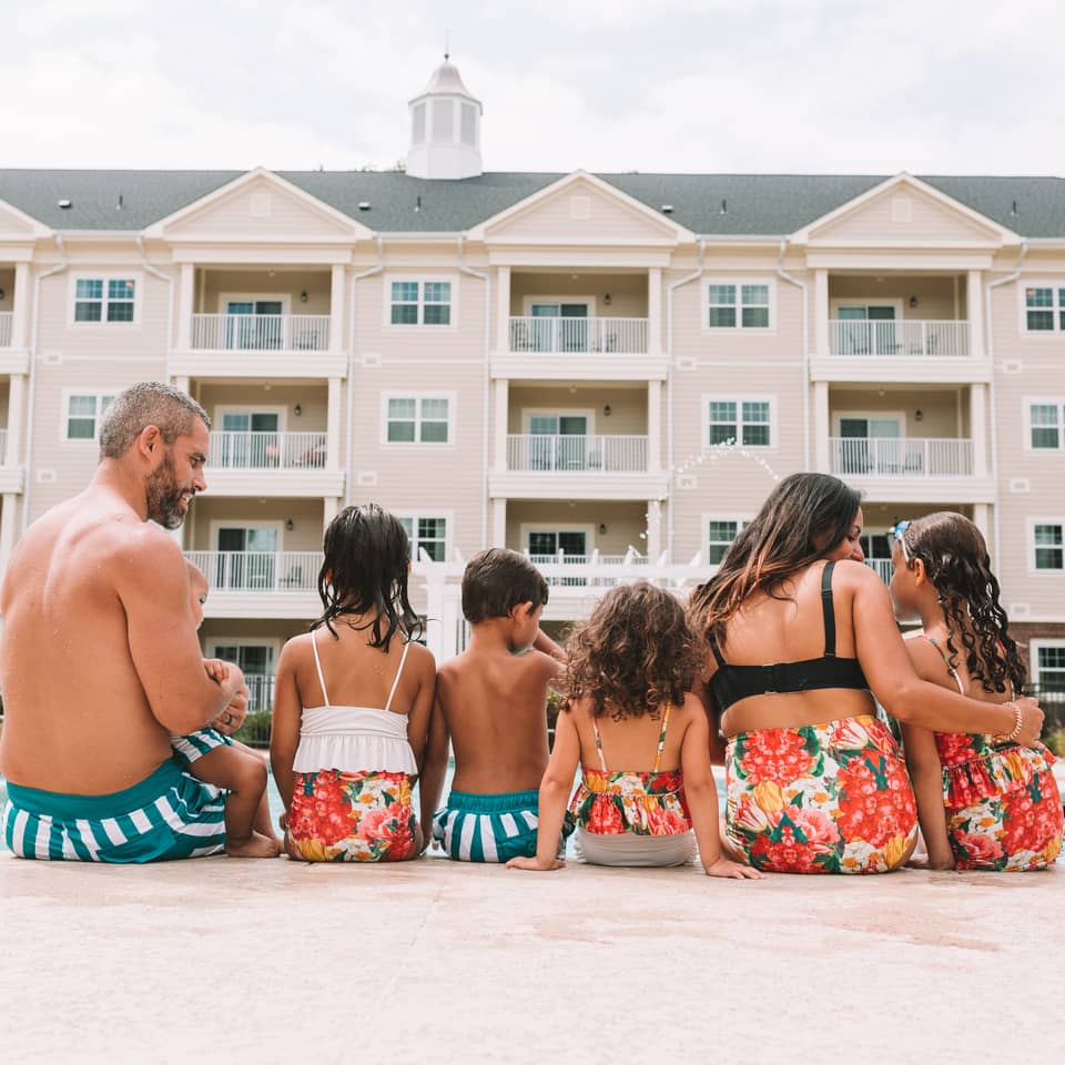 Mother, father, and their five children sitting at the edge of the pool at Holiday Inn Club Vacations Williamsburg Resort