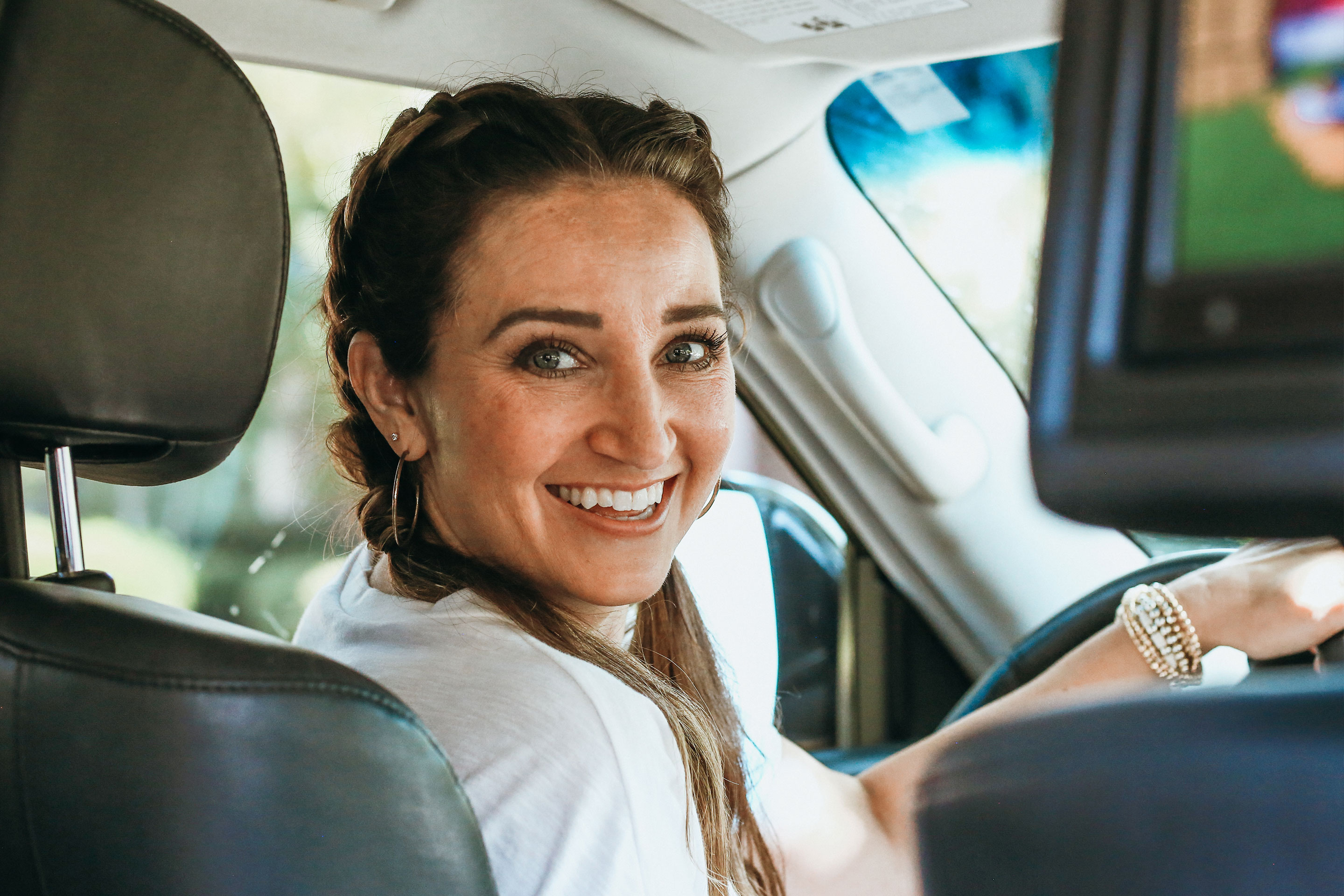 Mindy sits in the driver's seat of her SUV facing back.