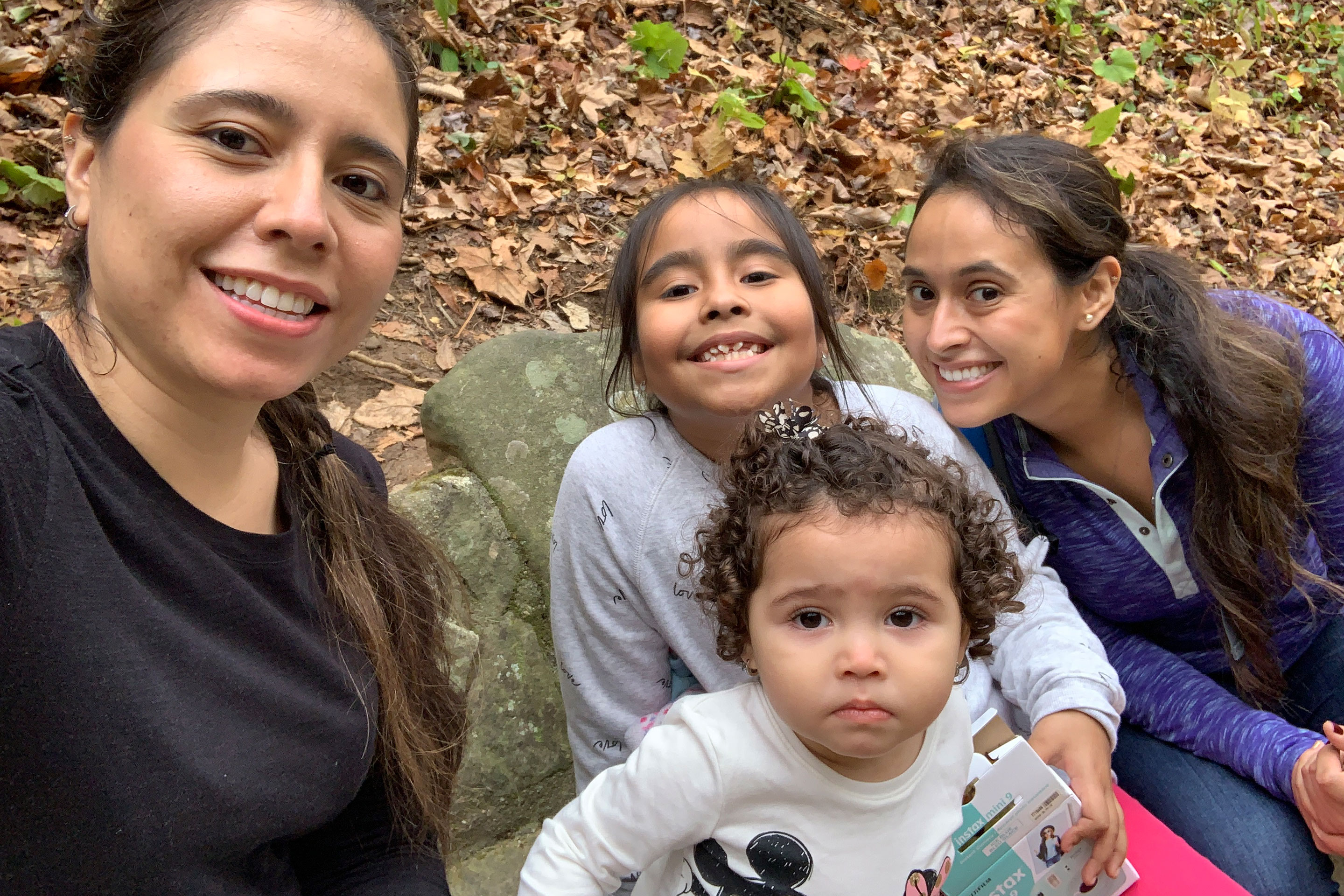 Featured author, Andrea Beltran (right), poses with her sister (left) and two nieces (middle) surrounded by dropped fall foliage.