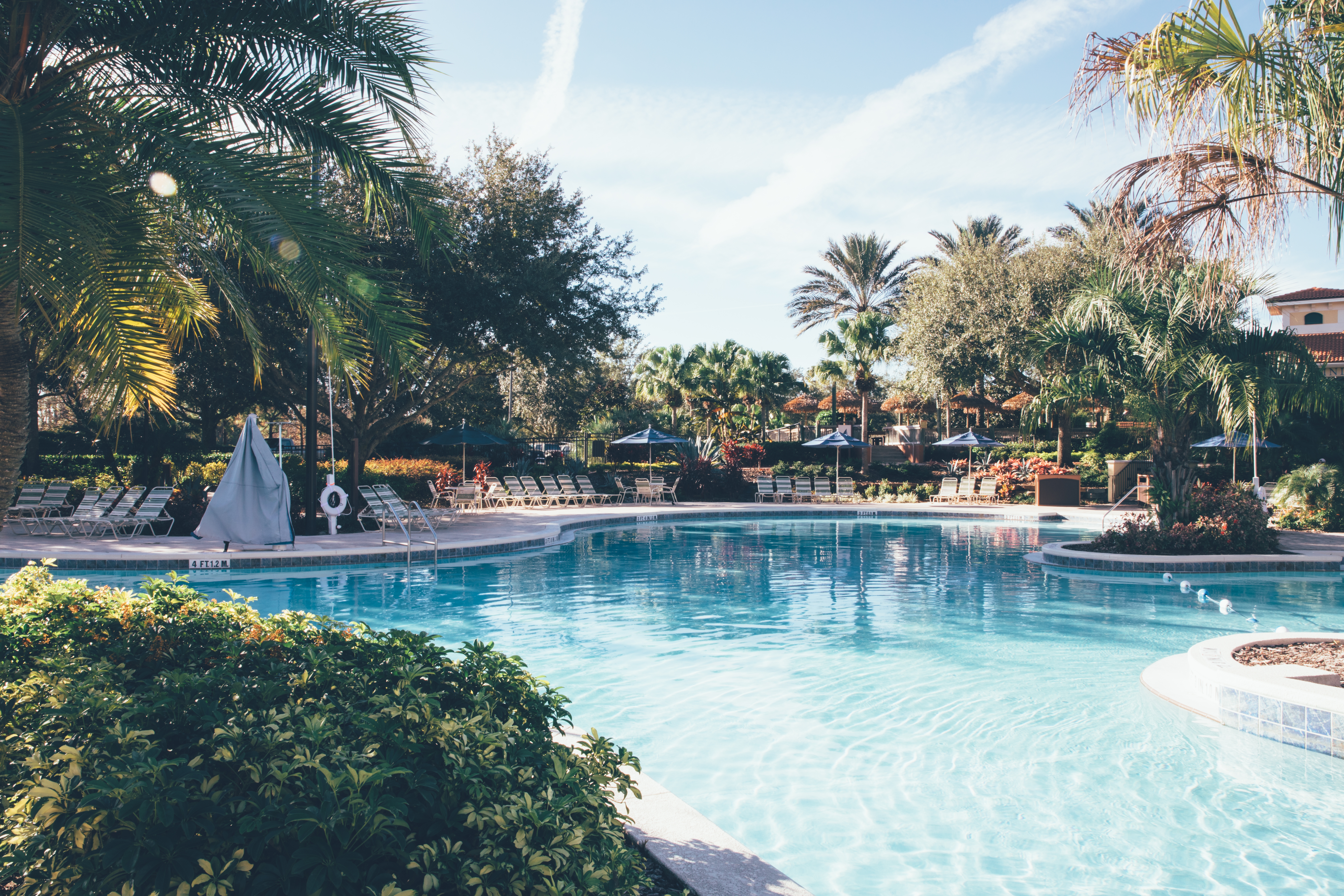 Pool with sun chairs surrounded by palm trees in River Island at Orange Lake Resort near Orlando, Florida.