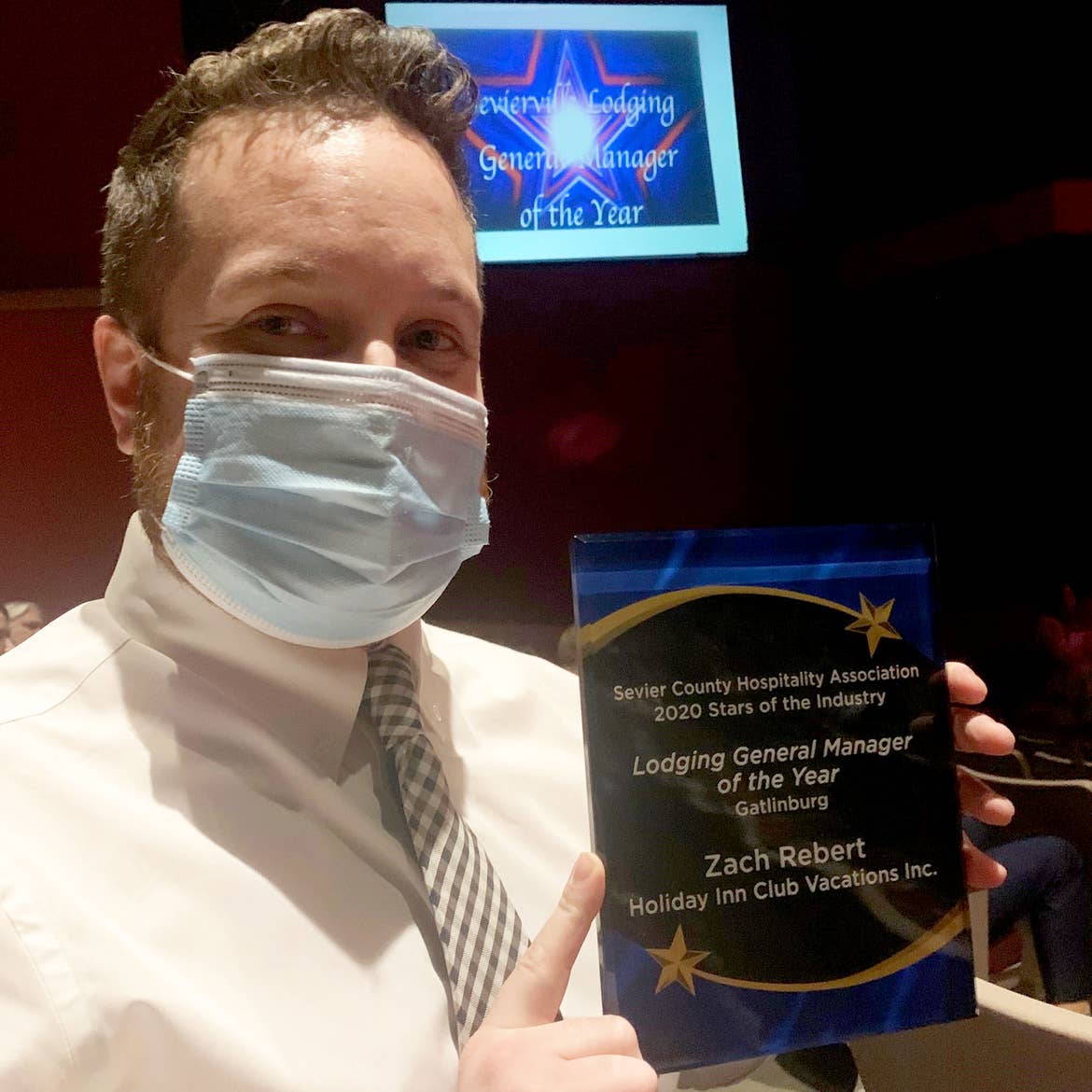 HICV general Manager, Zach Rebert, wears a mask while holding his 'Lodging General Manager of the Year' award.