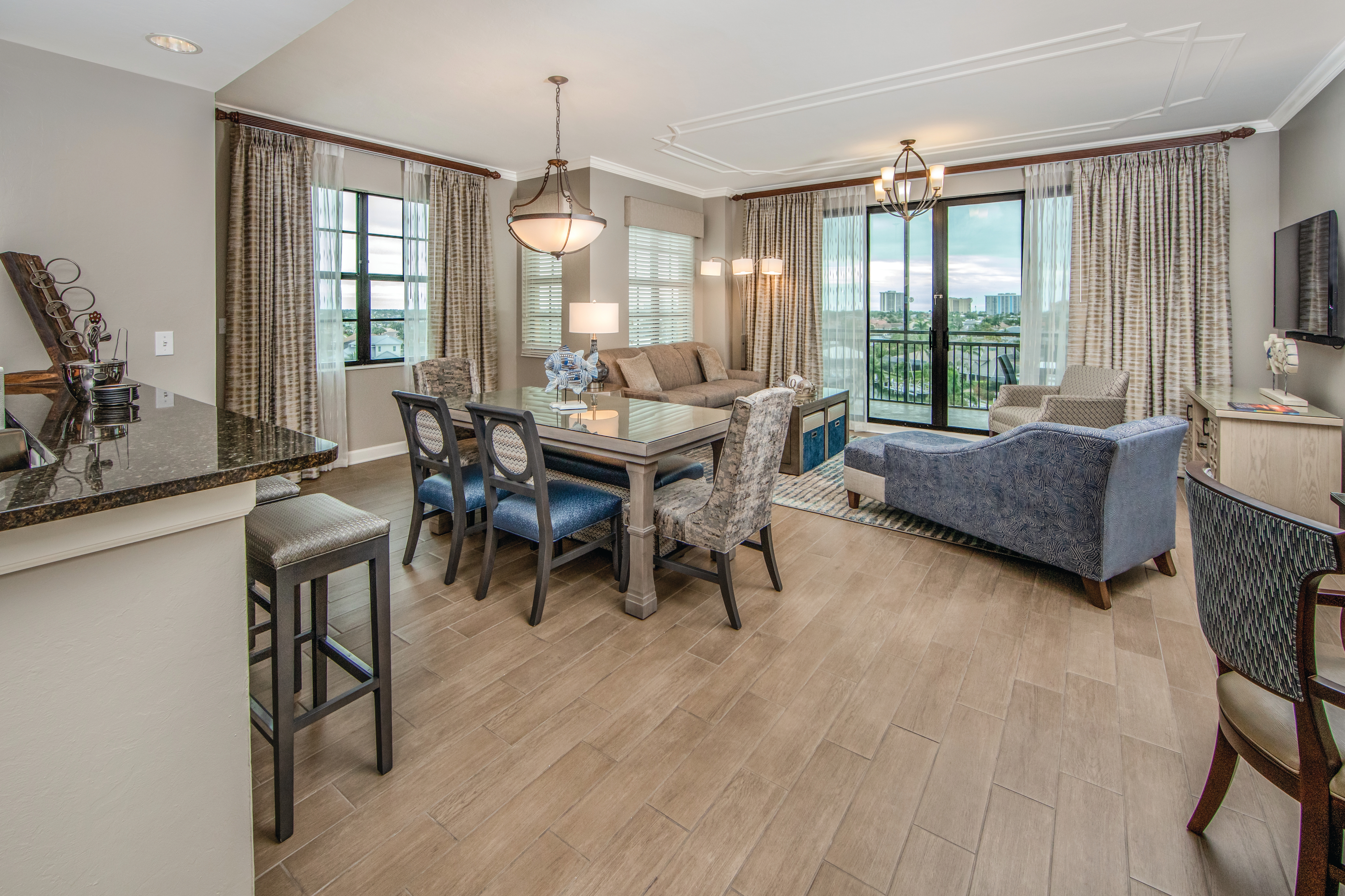 View of dining room table with six chairs and full living room in a three-bedroom villa at Sunset Cove Resort in Marco Island, Florida